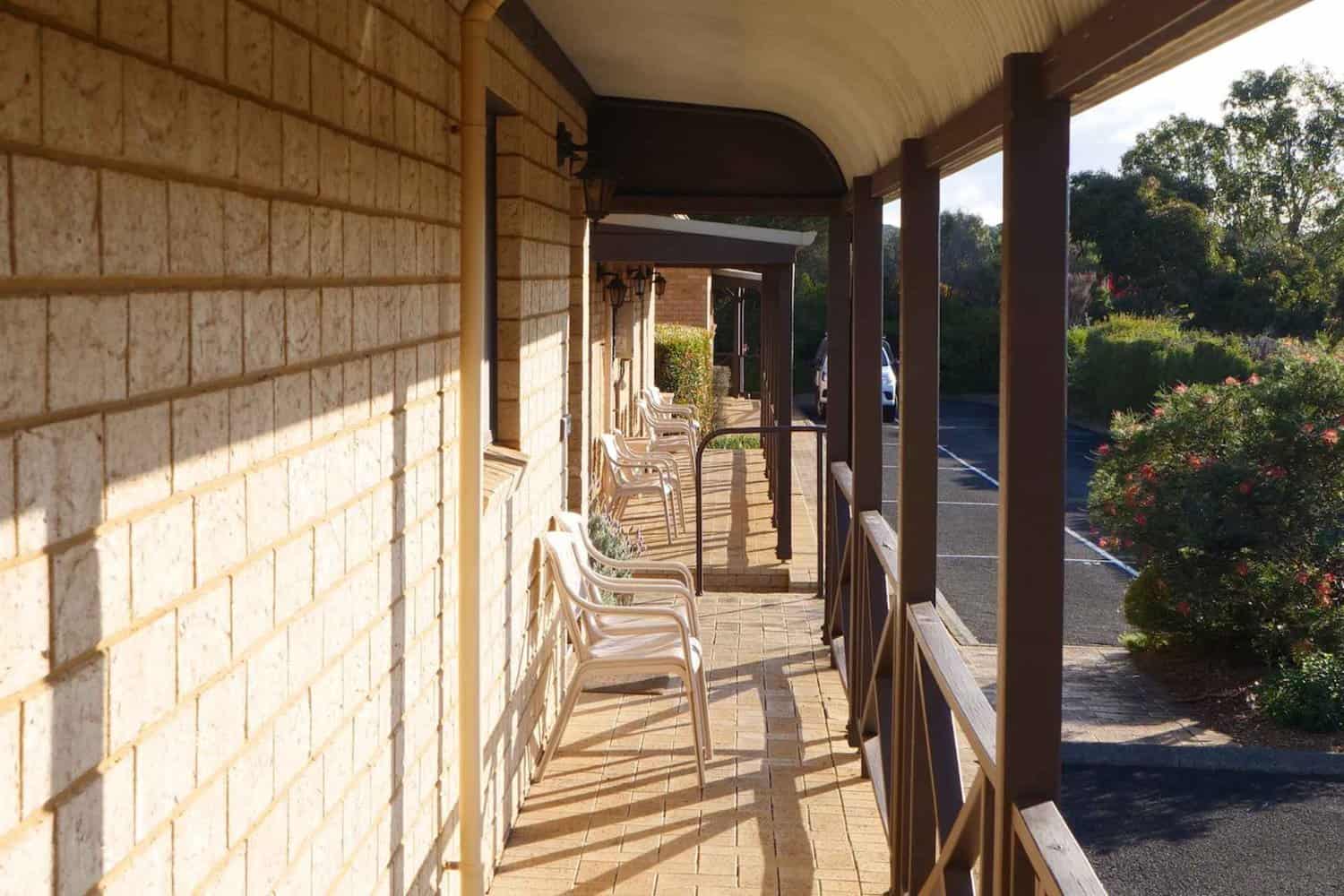 Inviting balcony at a Margaret River accommodation with a row of white chairs facing a garden.